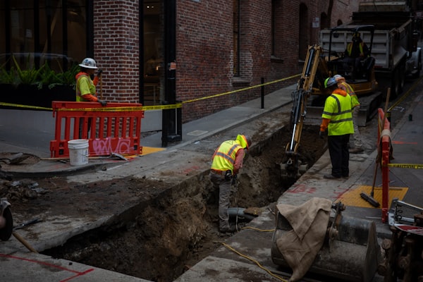 Construction workers digging trench for sewer pipe installation